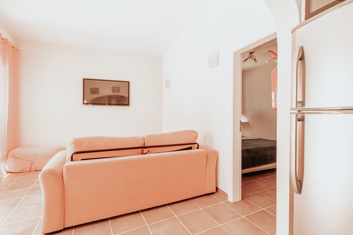 The sunlit living room at Casa do Vale, with a soft sofa, warm afternoon light, and a calm tiled floor
